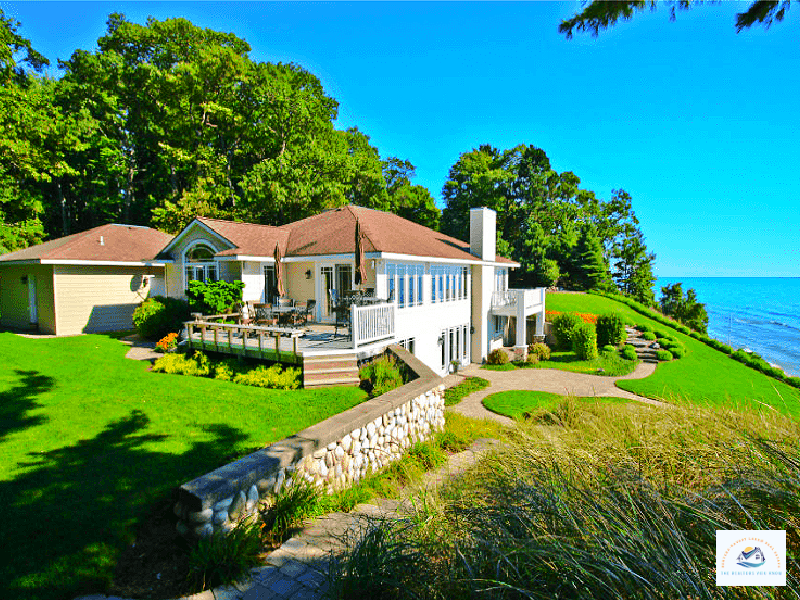 A breathtaking luxury waterfront home in West Bloomfield, MI, overlooking Pine Lake with a stunning elevated view. The property features a spacious deck, manicured landscaping, and a stone pathway leading to the water’s edge. With large windows and an open design, this lakefront home offers a perfect blend of elegance and natural beauty, ideal for those seeking premium Michigan lake real estate…