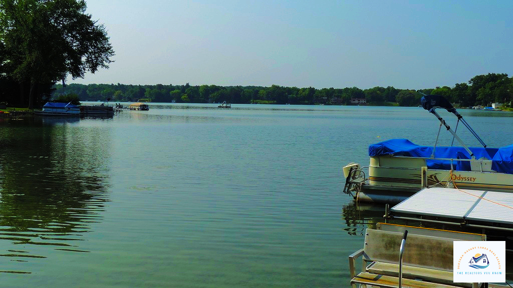 A peaceful dock on a West Bloomfield, MI lake, with pontoon boats ready for a relaxing day on the water. This prime location is ideal for homebuyers seeking waterfront homes with private lake access…